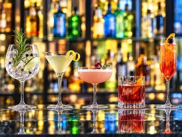 des verres de cocktails devant un mur de bouteilles